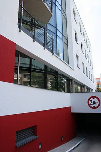 Fassadenecke mit Balkonen über der Tiefgaragenzufahrt mit Höhenbegrenzung auf 2,10 Meter