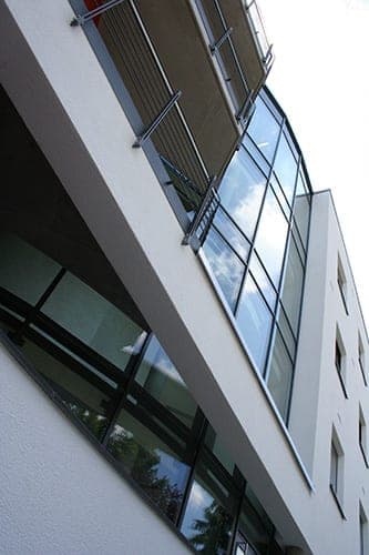 Blick von unten auf die gerundete Glasfassade mit Balkonen und auskragender Deckenplatte
