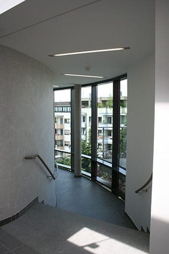 Treppenhaus mit gerundeter raumhoher Verglasung und Blick auf die Nachbarbebauung in Mögeldorf