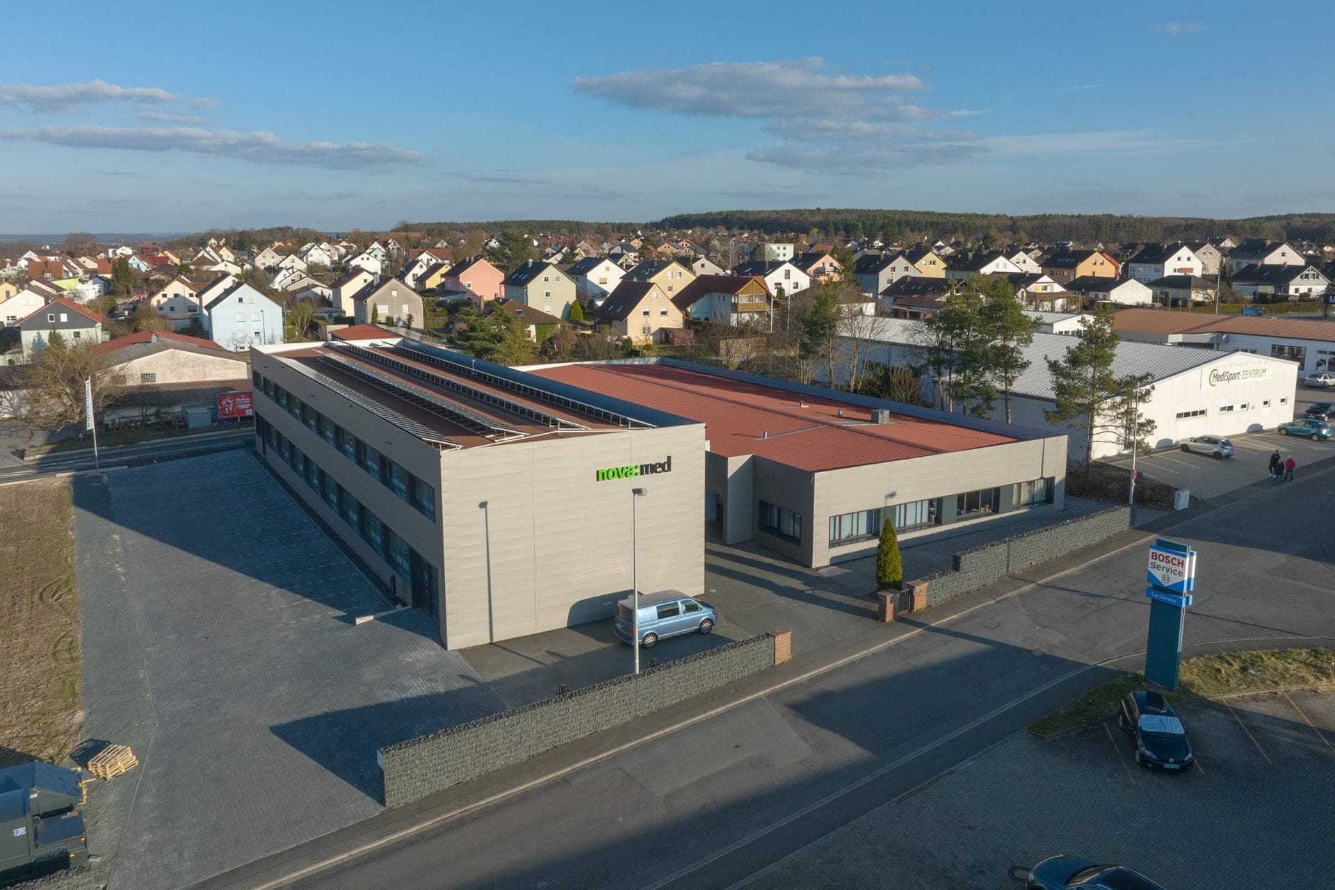 Aerial view of the refurbished office and warehouse building with solar panels on the roof and nova:med lettering