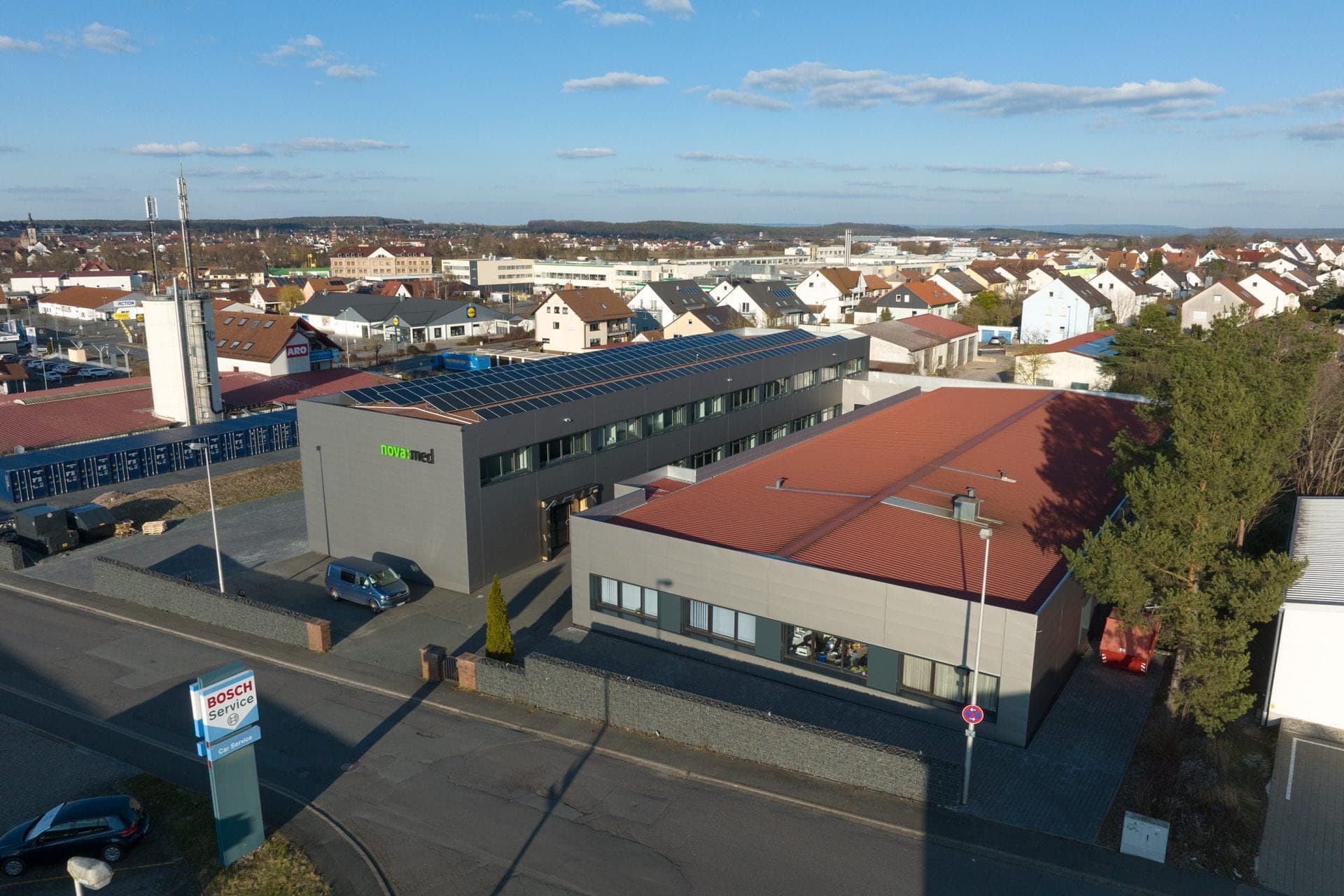 Aerial view across the building and the low hall with its red roof towards the town of Höchstadt an der Aisch