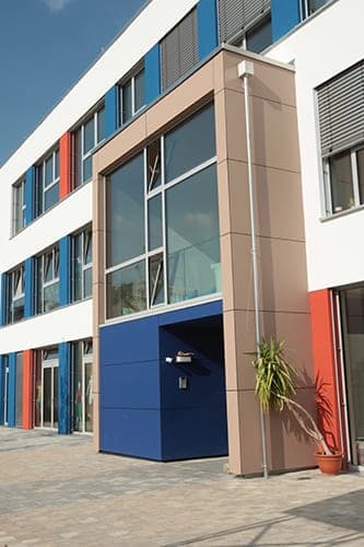 Entrance with a blue-clad porch beneath the glazed, sand-coloured projecting stair tower