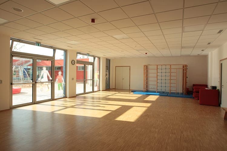 Multi-purpose room with parquet floor, wall bars and full-height glazed doors to the schoolyard