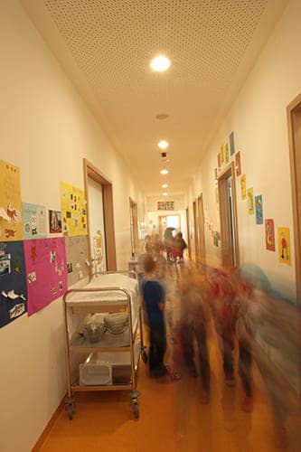 Corridor with children's drawings on the walls, a serving trolley and children on the move