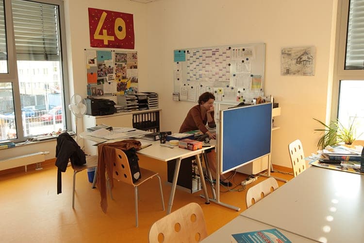 Office with desks, pinboards, a timetable board and a blue partition screen