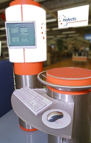 Terminal with screen, keyboard and mouse on a light column, with a Profectis sign in the background