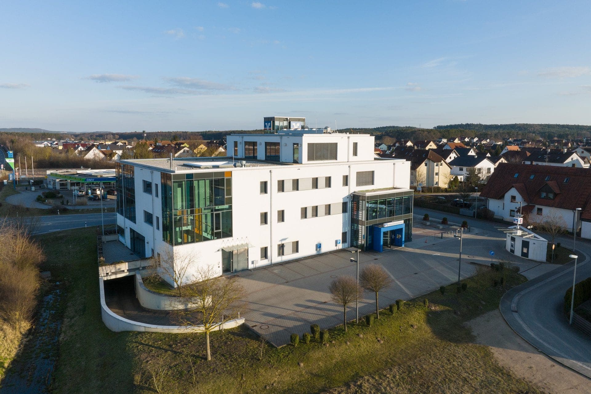 Aerial view of the stepped white volumes with access ramp, forecourt and the edge of Hessdorf behind