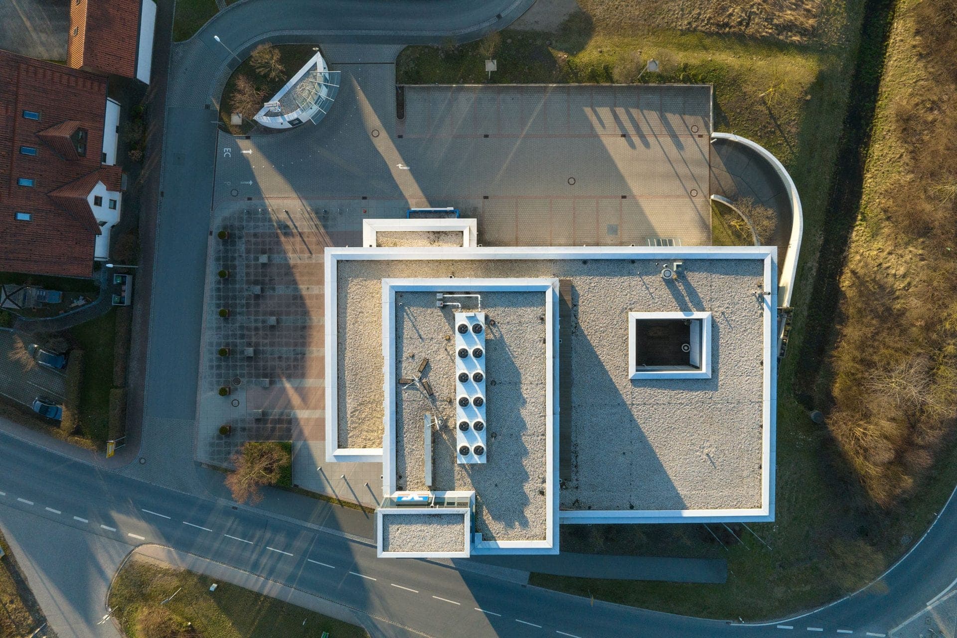 Bird's-eye view straight down onto the interlocking roofs with a light well and the paved forecourt