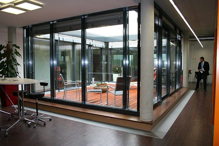 Glazed inner courtyard with timber decking and seating set within the office floor with wooden flooring