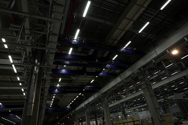 Untersicht der Hallendecke mit blauen Kranbrücken, Lichtbändern und Kranbahnträgern auf Betonstützen