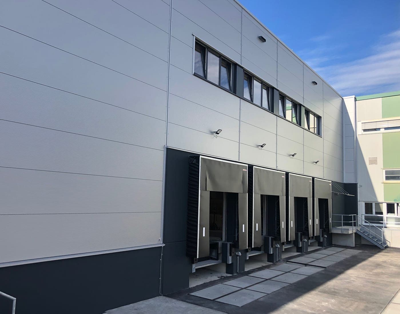 Oblique view of the loading bays with four dock shelters on the light grey panel façade