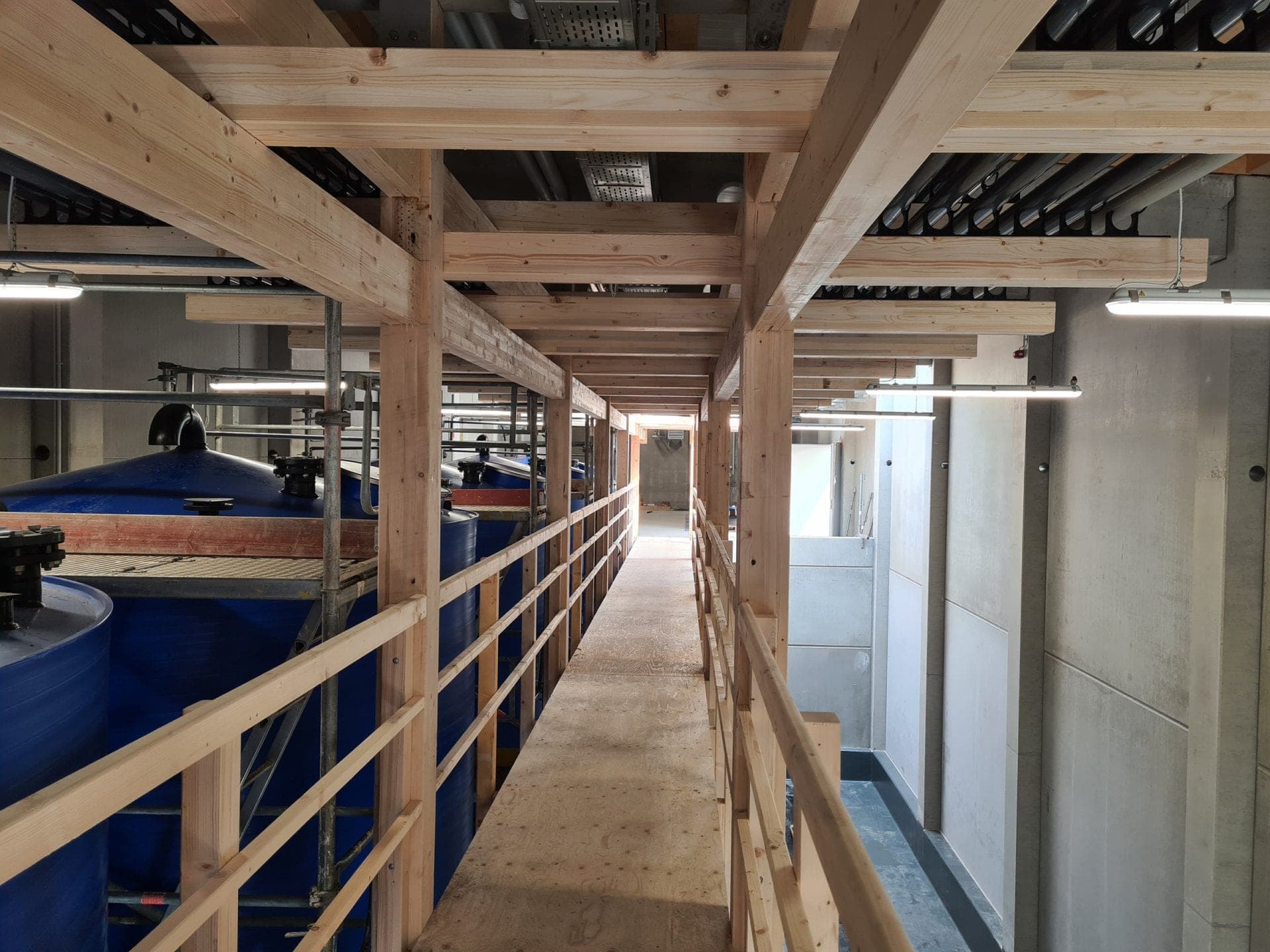 Begehbarer Holzsteg über den blauen Lagerbehältern innerhalb der Abfüllanlage in Nürnberg