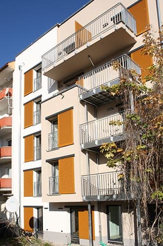 Rear of the residence with sliding shutters, stacked balconies and a façade with climbing plants