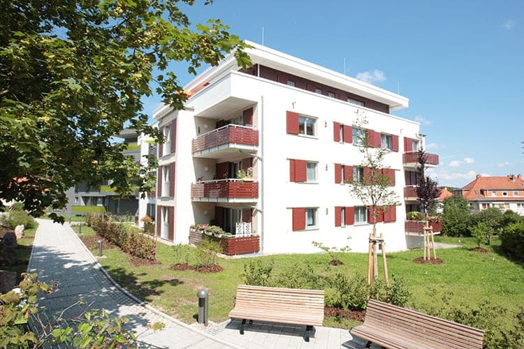 Garden side of the housing block with lawn, benches and a paved path in Ilmenau