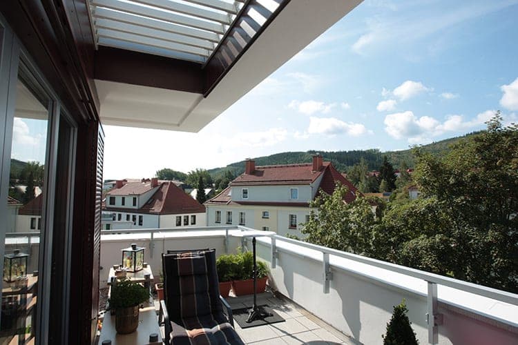Roof terrace with a lounger and a view over the neighbouring roofs to the wooded hills around Ilmenau