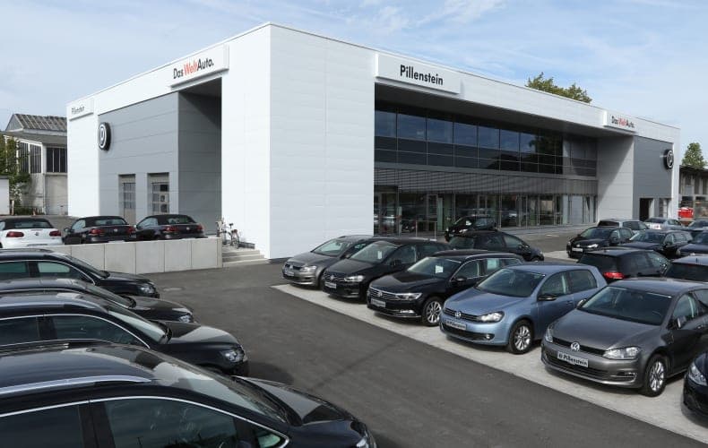 Autohaus Pillenstein in Fürth, Ansicht der weißen Metallfassade mit verglastem Schauraum und Fahrzeugen davor