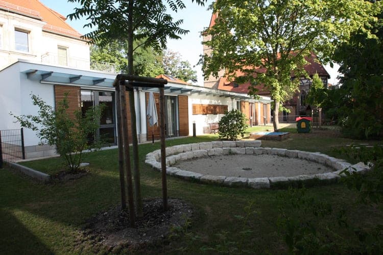 Johanneskirche parish centre in Nuremberg, view from the garden with a sand play area and mature trees